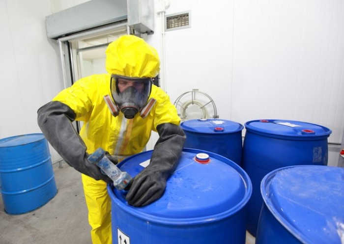 Mann in Schutzanzug entsorgt Chemikalien